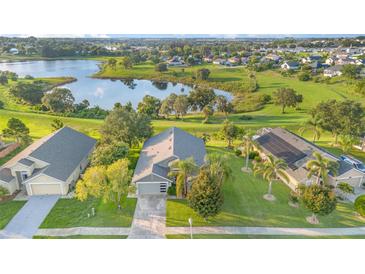 Stunning aerial view of home and lake, showcasing a well-manicured lawn and beautiful surrounding neighborhood at 1315 Vista Del Lago Blvd, Dundee, FL 33838