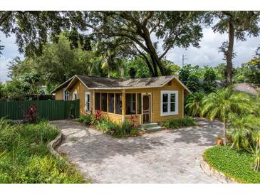 Charming cottage-style home with a screened porch and a brick driveway, surrounded by lush landscaping at 2320 E Crystal Lake Ave, Orlando, FL 32806