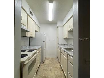 Functional kitchen features tile floors, stainless steel sink, and white cabinets for a clean, classic look at 415 Wymore Rd # 101, Altamonte Springs, FL 32714