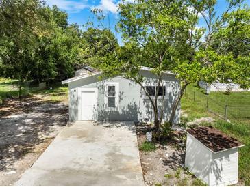 Exterior view of home with a concrete drive, small shed and mature tree in a landscaped yard at 4925 Catfish Rd, Lake Wales, FL 33898