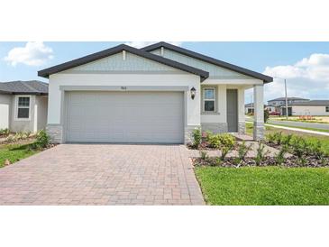Charming single-Gathering home featuring a two-car garage, stone accents, and a well-manicured lawn at 903 Donahue Pass, Lake Hamilton, FL 33851