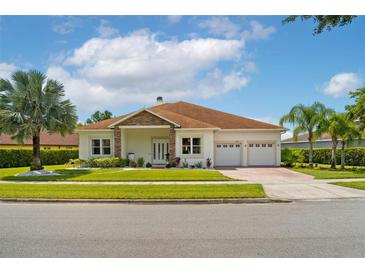 Charming single-story home with a well-manicured lawn, stone accents, and a three-car garage at 9821 Caroline Park Dr, Orlando, FL 32832