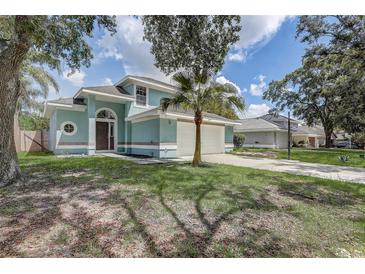 Charming two-story home featuring an attached two-car garage and mature trees in a manicured front yard at 10599 Satinwood Cir, Orlando, FL 32825