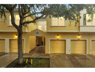 Inviting yellow townhome with individual garages, a walkway to front door and mature landscaping at 2820 Oakwater Dr # 2820, Kissimmee, FL 34747