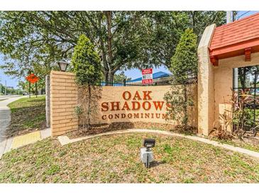 Attractive signage for Oak Shadows Condominiums with brick and stucco construction and mature landscaping at 2850 N Powers Dr # 74, Orlando, FL 32818