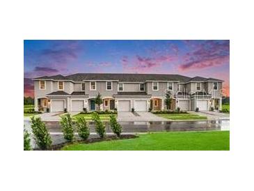 Modern townhome exteriors with individual garages and manicured lawns on a sunny day at 3603 Davenport Creek Ct, Kissimmee, FL 34746