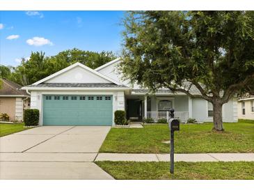 Charming single-story home featuring a teal garage door, well-manicured lawn, and mature landscaping at 3610 Doe Run Dr, St Cloud, FL 34772