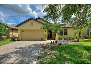 Charming single-story home with a paver driveway, attached garage, and tropical landscaping at 519 Cadiz Dr, Davenport, FL 33837