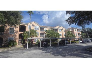 Condo exterior featuring covered parking, balconies, and mature trees at 13584 Turtle Marsh Loop # 12, Orlando, FL 32837