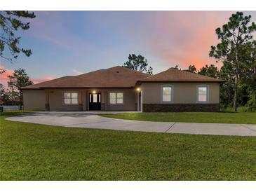 Inviting single-story home with a large front yard and a driveway, set against a beautiful sunset backdrop at 19606 Reynolds Pkwy, Orlando, FL 32833