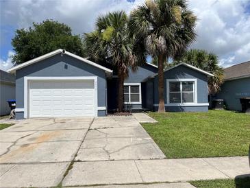 Charming single-story home featuring a well-maintained lawn, two palm trees, and a quaint blue exterior at 2833 Woodruff Dr, Orlando, FL 32837