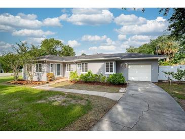 Charming gray single-story home with a well-manicured lawn, front garden, and attached garage at 311 Cortland Ave, Winter Park, FL 32789