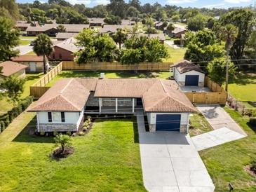 Expansive aerial view of a single-story home with a detached garage, fenced yard, and mature trees at 338 Henry Butts Dr, Daytona Beach, FL 32114