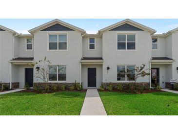 Charming two-story townhouse with landscaped yard and walkway leading to the front door at 5641 Brosnan Rd, St Cloud, FL 34771