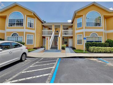 Exterior view of a sunny yellow condominium building with two stories and covered walkways to the entrance at 8709 Knightsbridge Ct # B, Kissimmee, FL 34747