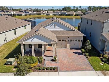 Beautiful exterior view of home with brick driveway, lake view, well-kept lawn, and two-car garage at 8935 Sonoma Coast Dr, Winter Garden, FL 34787