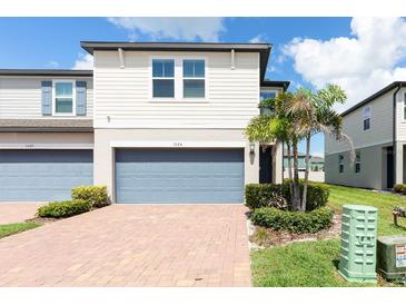 Charming townhouse showcasing a brick driveway and a serene front yard with lush landscaping and a two car garage at 1024 Desert Candle Dr, Ocoee, FL 34761
