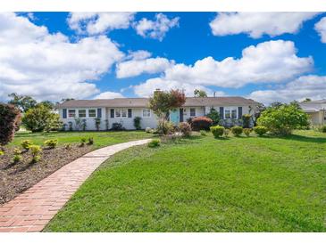Charming ranch-style home with a well-manicured lawn, brick walkway, and a bright turquoise front door at 1301 Fahnstock St, Eustis, FL 32726