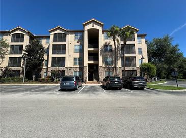 Exterior of a multi-story condo building with palm trees, covered walkways, and parking lot in front at 1370 Tuscan Ter # 2202, Davenport, FL 33896