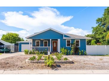 Charming blue home featuring a cozy front porch, manicured landscaping, and a welcoming entrance at 1609 E Kaley Ave, Orlando, FL 32806