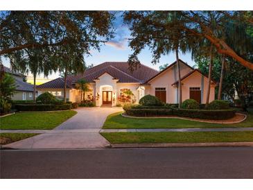 Elegant home featuring a red tile roof, lush landscaping, and a circular driveway at 9142 Southern Breeze Dr, Orlando, FL 32836