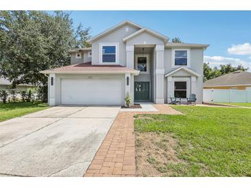 Charming two-story home featuring an attached garage, manicured lawn, and inviting front porch seating area at 12643 Lakebrook Dr, Orlando, FL 32828