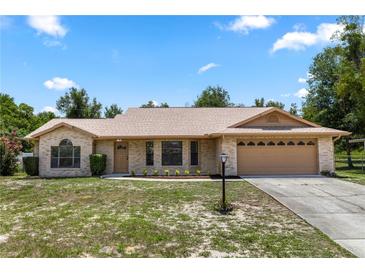 Charming single-story home with brick facade, attached two-car garage, and landscaped front yard on a sunny day at 1299 Buccaneer Ave, Deltona, FL 32725