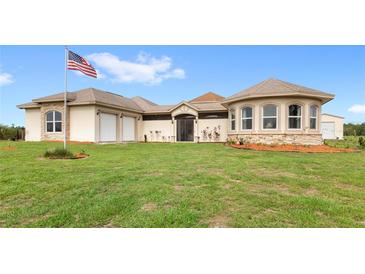 Stunning single-story home with attached garages and lush green lawn at 13023 Sweet Hill Rd, Polk City, FL 33868