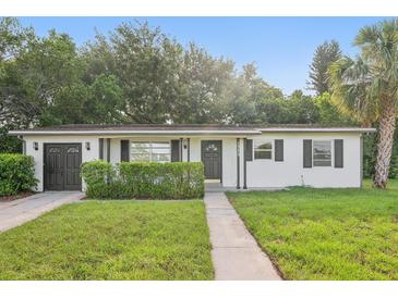Charming single-story home featuring a well-maintained lawn, dark shutters, and an attached garage at 1320 E Lombardy Dr, Deltona, FL 32725