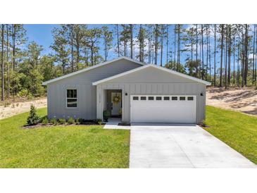Charming one-story home featuring gray siding, a two-car garage, and a well-manicured lawn with a tree-lined background at 13264 Sw 69Th Pl, Ocala, FL 34481