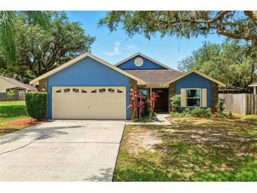 Charming single Gathering home with a beautiful blue exterior, mature trees, and a well maintained lawn at 171 Cedarpark Ln, Davenport, FL 33837