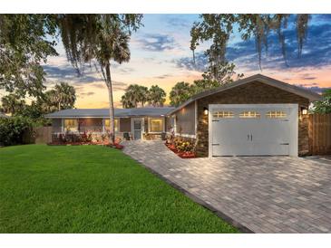 Charming single-story home with a paver driveway, attached garage, lush landscaping and beautiful curb appeal at 418 Acacia Cir, Port Orange, FL 32127