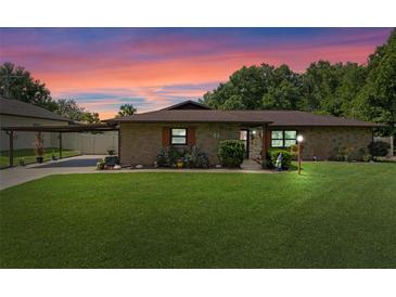 Charming brick home featuring a well-manicured lawn, covered carport, and inviting front garden at 51 Seminole Dr, Debary, FL 32713