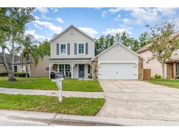 Charming two-story home featuring stone accents, a covered porch, and a well-maintained lawn at 1033 Mccully Ct, Oviedo, FL 32765