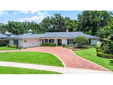Charming single-story home with a brick driveway, attached garage, manicured lawn, and lush landscaping at 2527 Shrewsbury Rd, Orlando, FL 32803