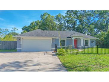 Charming single-story home with a manicured lawn, gray exterior, red door and two-car garage at 4911 Ne 7Th St, Ocala, FL 34470