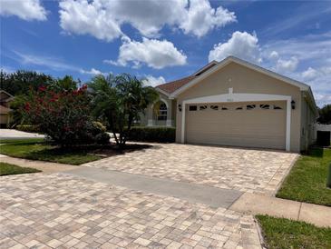 Charming home with a brick driveway, lush landscaping, and a two-car garage on a beautiful day at 9003 Pecky Cypress Way, Orlando, FL 32836