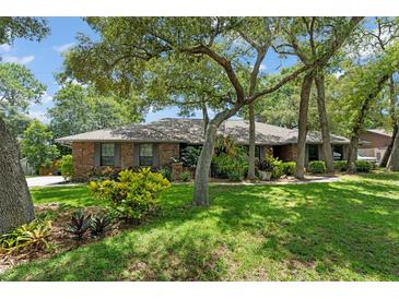 Charming brick home featuring a lush, green lawn and mature trees providing ample shade at 473 Burnt Tree Ln, Apopka, FL 32712