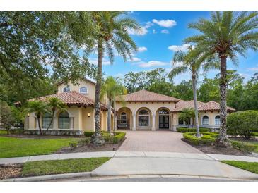 Stunning Mediterranean-style home featuring a red tile roof, arched entryways, and lush landscaping with palm trees at 5413 Via Veneto Ct, Sanford, FL 32771
