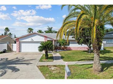 Charming single-story home with a lush front yard, white exterior with pink accents, and a two-car garage at 109 Woodfield Ct, Sanford, FL 32773