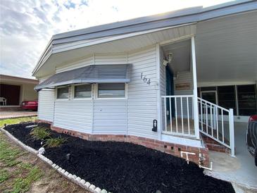 Charming home exterior featuring meticulous landscaping, a covered porch, and vinyl siding at 164 Royal Palm Dr, Leesburg, FL 34748