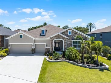 Beautiful single-Gathering home with a manicured lawn, stone accents, and a spacious three-car garage at 17290 Hickory Wind Dr, Clermont, FL 34711