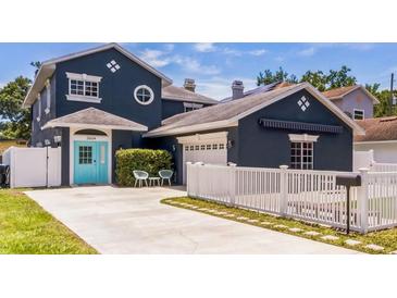 Charming two-story home features a blue exterior with a manicured lawn and white picket fence at 2604 Marble Ave, Orlando, FL 32803