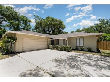 Charming single-story home featuring a large driveway and an attached garage, surrounded by mature trees and lush landscaping at 917 Great Bend Rd, Altamonte Springs, FL 32714