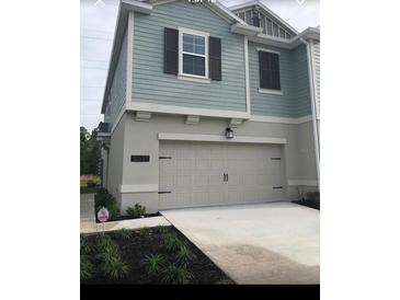 Charming two-story home with a light-colored exterior, a garage, and dark window shutters at 12337 Turtle Grass Dr, Orlando, FL 32824