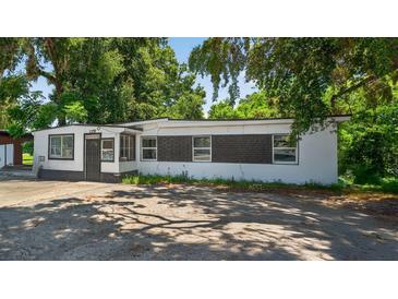 Charming single-story home with white and black exterior paint, surrounded by mature trees at 1257 N Pine Hills Rd, Orlando, FL 32808