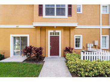 Inviting condo entrance featuring a red door and lush landscaping at 2280 San Vital Dr # 101, Kissimmee, FL 34741