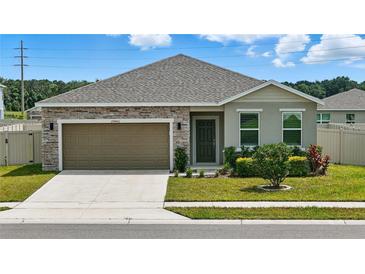 Charming single-story home featuring a stone facade, attached garage, and well-manicured lawn at 24401 Sunnys Halo Way, Sorrento, FL 32776