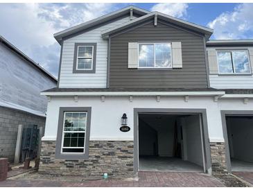 Charming two-story townhome featuring stone accents, an attached garage, and neutral-toned siding at 5085 Prairie Preserve Run, St Cloud, FL 34772