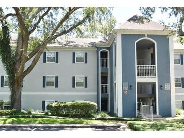 Multi-Gathering condo building with blue and gray facade, balcony, and lush, mature landscaping at 7104 Olympia Ct # 7104, Longwood, FL 32779